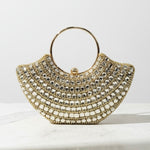 Gold beaded handbag on a marble surface with a white background