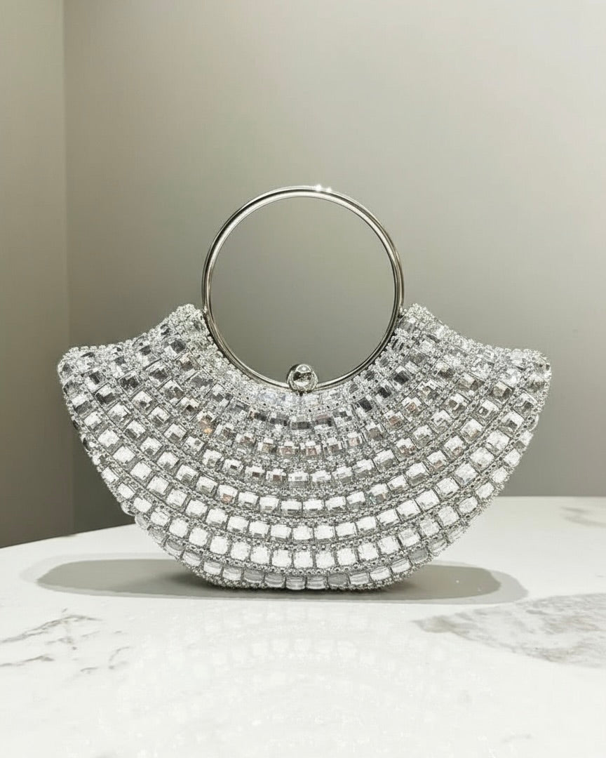 Silver handbag with circular handle on a marble surface