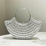 Silver handbag with circular handle on a marble surface