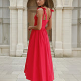 Woman in a red midi dress standing in front of classical architecture