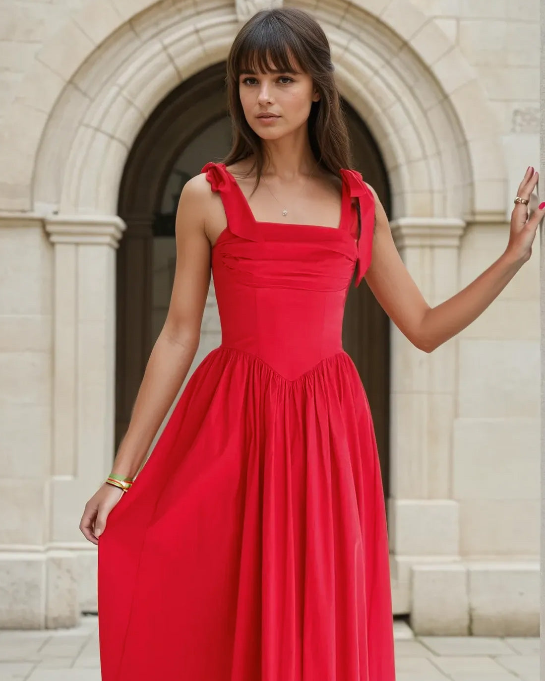 Woman in a red midi dress standing in front of classical architecture
