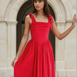 Woman in a red midi dress standing in front of classical architecture