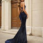 Woman wearing a navy blue glitter formal evening gown in front of classical architecture.