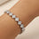 Silver bracelet with diamond-like stones on a wrist against a neutral background
