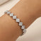 Silver bracelet with diamond-like stones on a wrist against a neutral background
