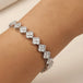 Silver bracelet with diamond-like stones on a wrist against a neutral background