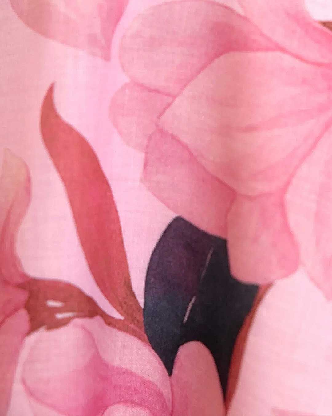 A close-up of a pink floral fabric print featuring soft pink petals and a dark plum-colored center.