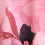A close-up of a pink floral fabric print featuring soft pink petals and a dark plum-colored center.