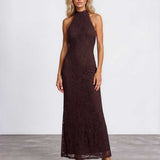 A woman modeling a sleeveless, high-neck, floor-length lace maxi dress in a deep dark brown color, standing against a light gray studio background.
