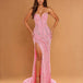 A woman models a strapless pink evening gown with silver sequin embellishments, a sweetheart neckline, and a high thigh slit, set against a solid tan studio background.