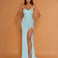 A woman modeling a strapless light blue sequined gown with a sweetheart neckline, ruched bodice, high thigh slit, and floor-length train against a warm tan studio backdrop.