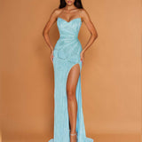 A woman modeling a strapless, light blue sequined gown with a sweetheart neckline, ruched bodice, high thigh slit, and floor-length train against a solid tan studio backdrop.