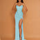 A woman modeling a strapless, light blue sequined gown with a sweetheart neckline, ruched bodice, high thigh slit, and floor-length train against a solid tan studio backdrop.