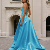 Woman wearing a blue formal strapless gown standing on a stone pavement.