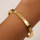 Gold bracelet with diamond accents on a wrist against a beige background