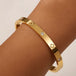 Gold bracelet with diamond accents on a wrist against a beige background