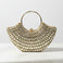 Gold beaded handbag on a marble surface with a white background