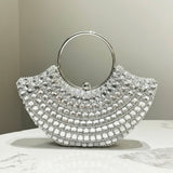 Silver handbag with circular handle on a marble surface