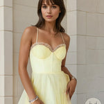 Woman wearing a light yellow lace-trimmed nightgown against a beige wall.