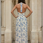 Woman wearing a halterneck floral white and blue dress back view