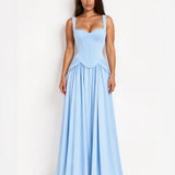 A woman modeling a light blue sleeveless maxi dress with a fitted corset-style bodice and a flowing skirt, standing against a plain white studio background.