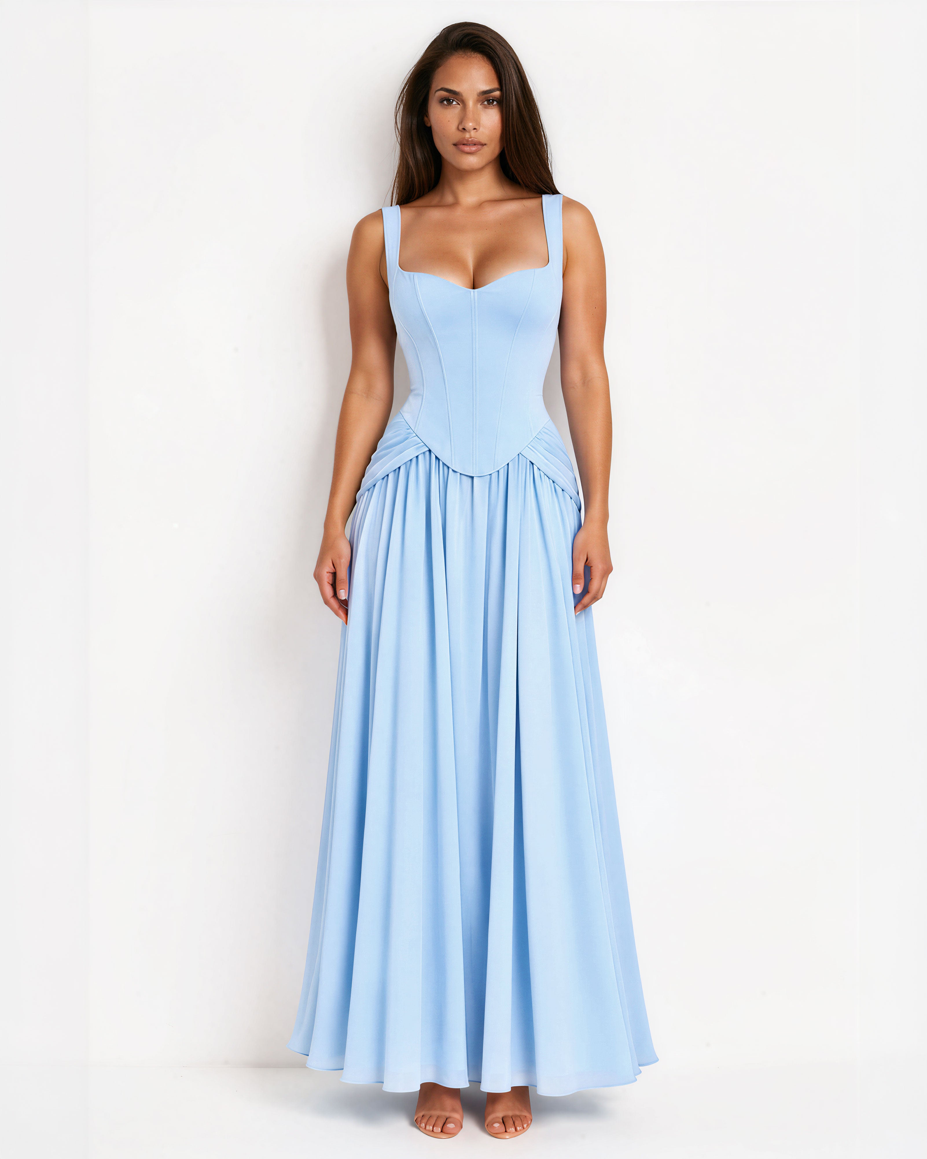 A woman modeling a light blue sleeveless maxi dress with a fitted corset-style bodice and a flowing skirt, standing against a plain white studio background.