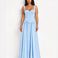 A woman modeling a light blue sleeveless maxi dress with a fitted corset-style bodice and a flowing skirt, standing against a plain white studio background.