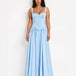 A woman modeling a light blue sleeveless maxi dress with a fitted corset-style bodice and a flowing skirt, standing against a plain white studio background.