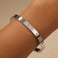 Silver bracelet with diamond accents on a wrist against a beige background