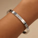 Silver bracelet with diamond accents on a wrist against a beige background