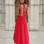 Woman in a red midi dress standing in front of classical architecture