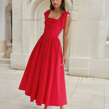 Woman in a red midi dress standing in front of classical architecture