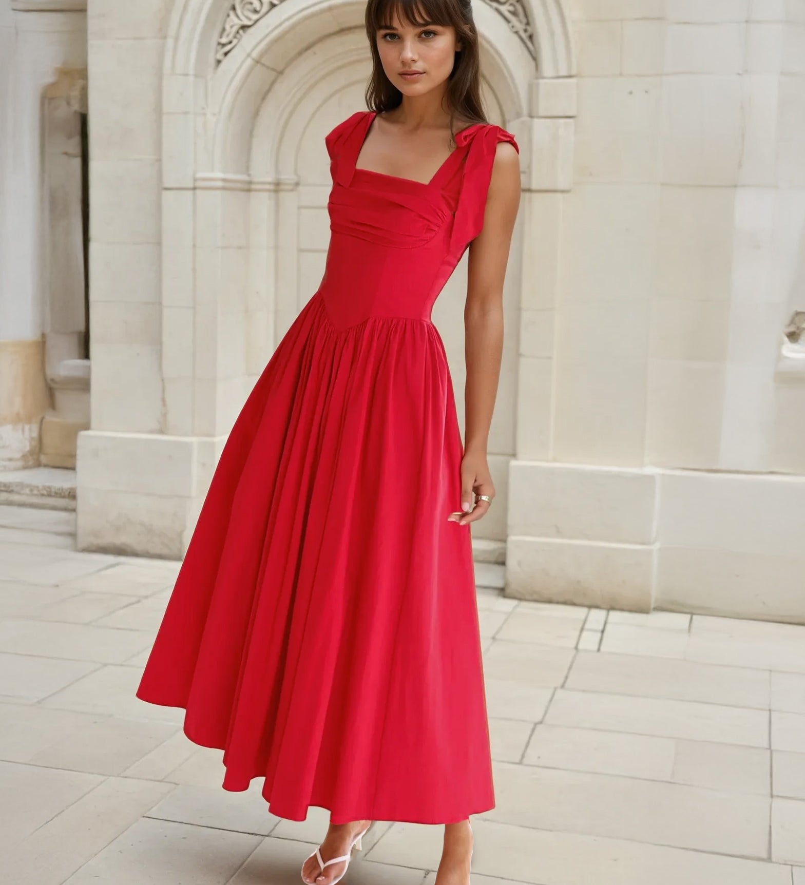 Woman in a red midi dress standing in front of classical architecture