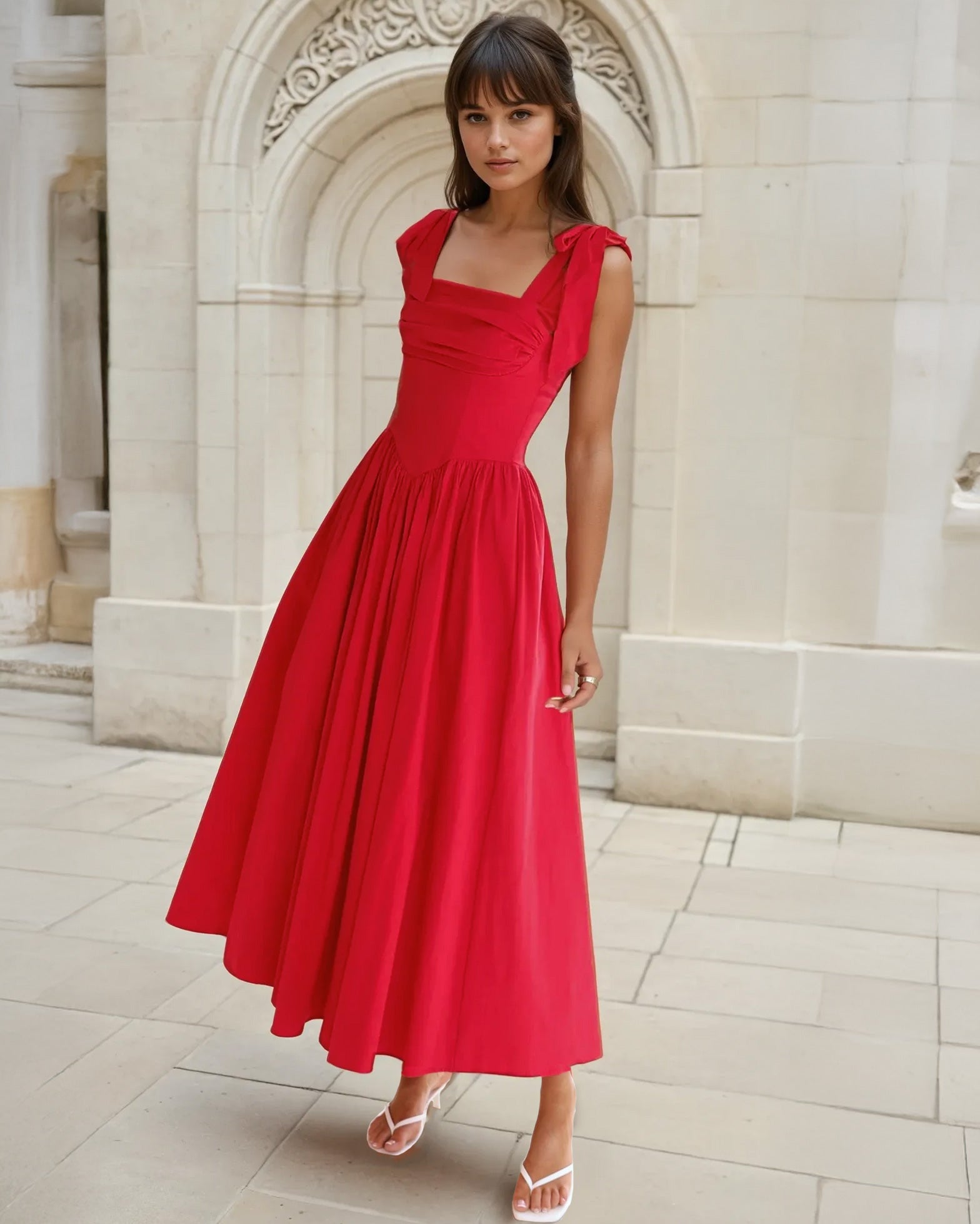 Woman in a red midi dress standing in front of classical architecture